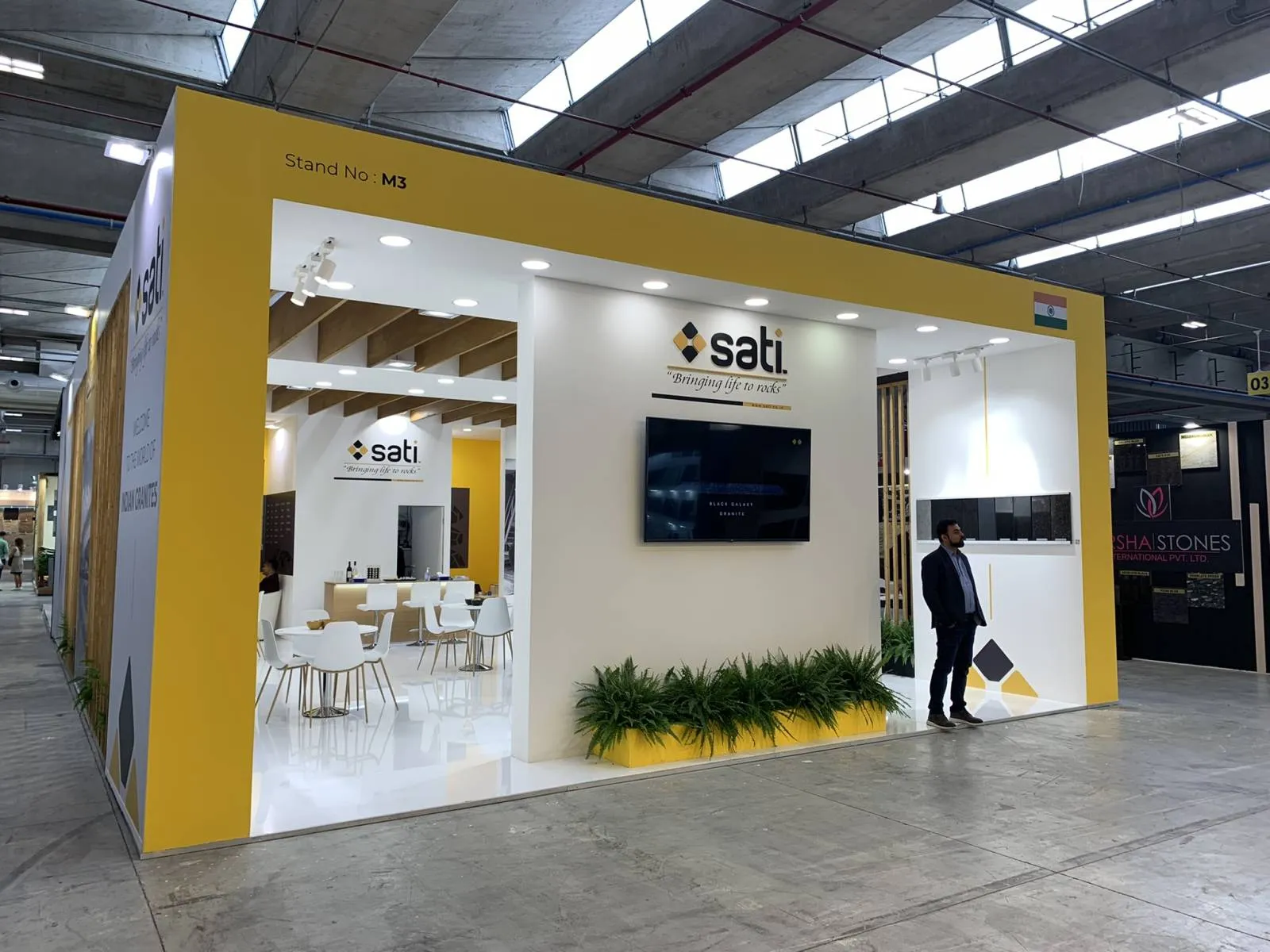 Stand Sati a Marmomac, facciata gialla con insegna e area lounge interna