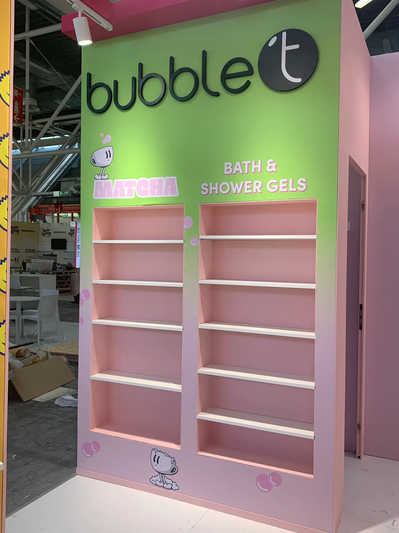 Stand bubble t a Cosmoprof in fase di allestimento, parete verde con scaffalature per prodotti Matcha e Bath & Shower Gels