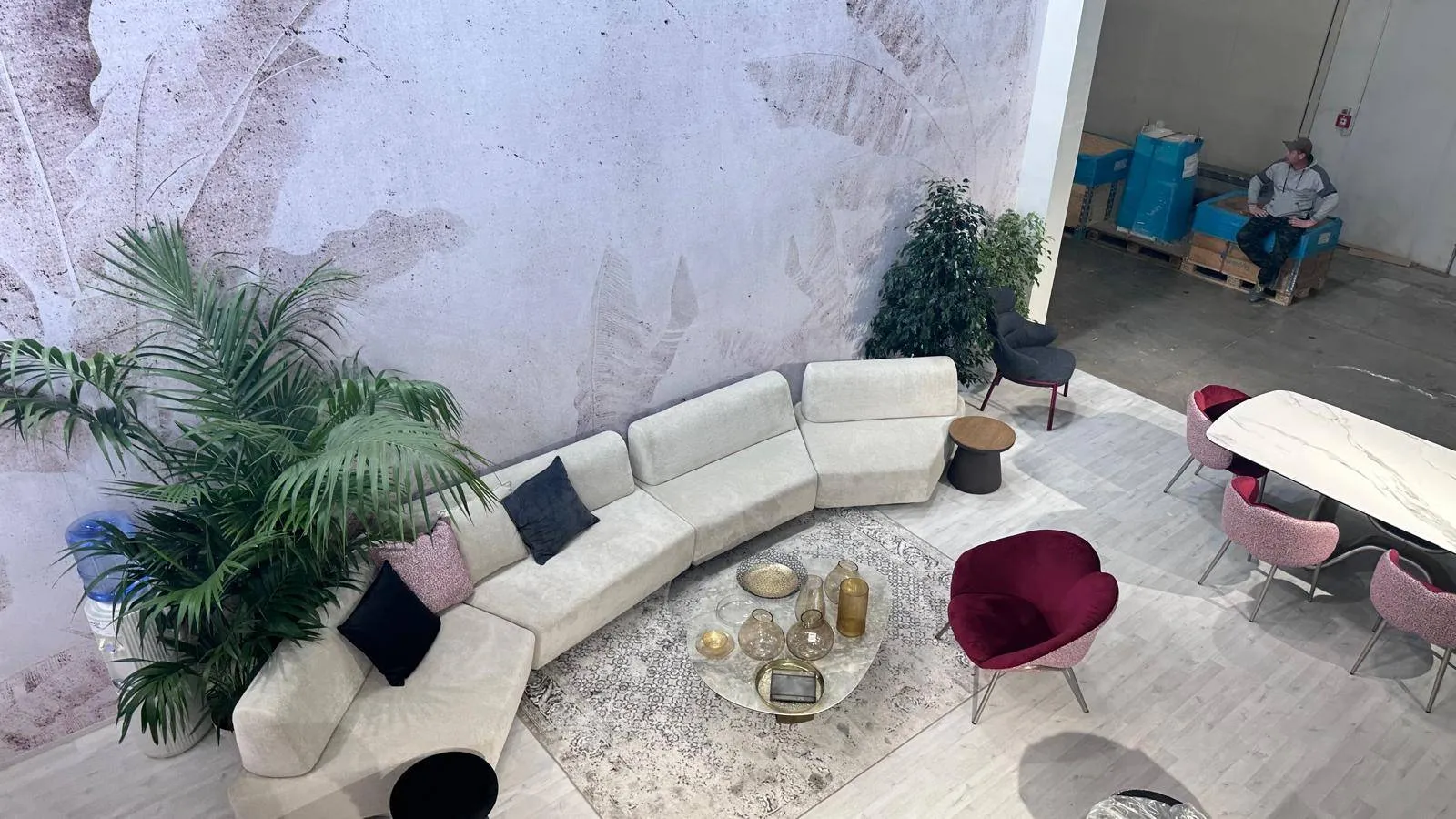 Area lounge al piano mezzanino dello stand Briolina al Salone del Mobile, divano e parete botanica