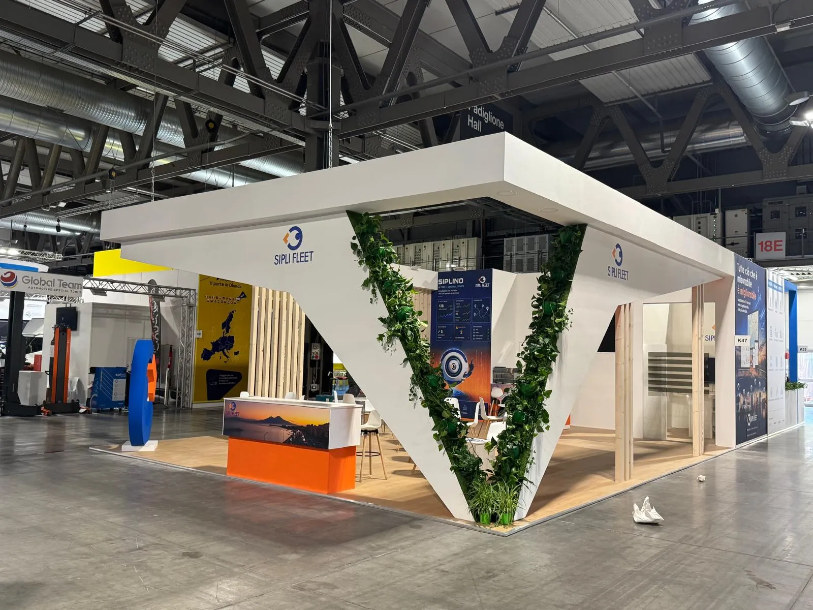 Stand SIPLI FLEET realizzato a Transpotec, vista d'angolo opposta con banco reception, colonna a V rivestita di edera e pannello Siplino